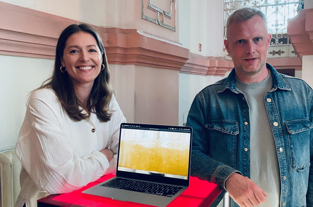 Psylink's startup founders, woman and man stands next to the table on witch is a computer and looks into the camera smiling