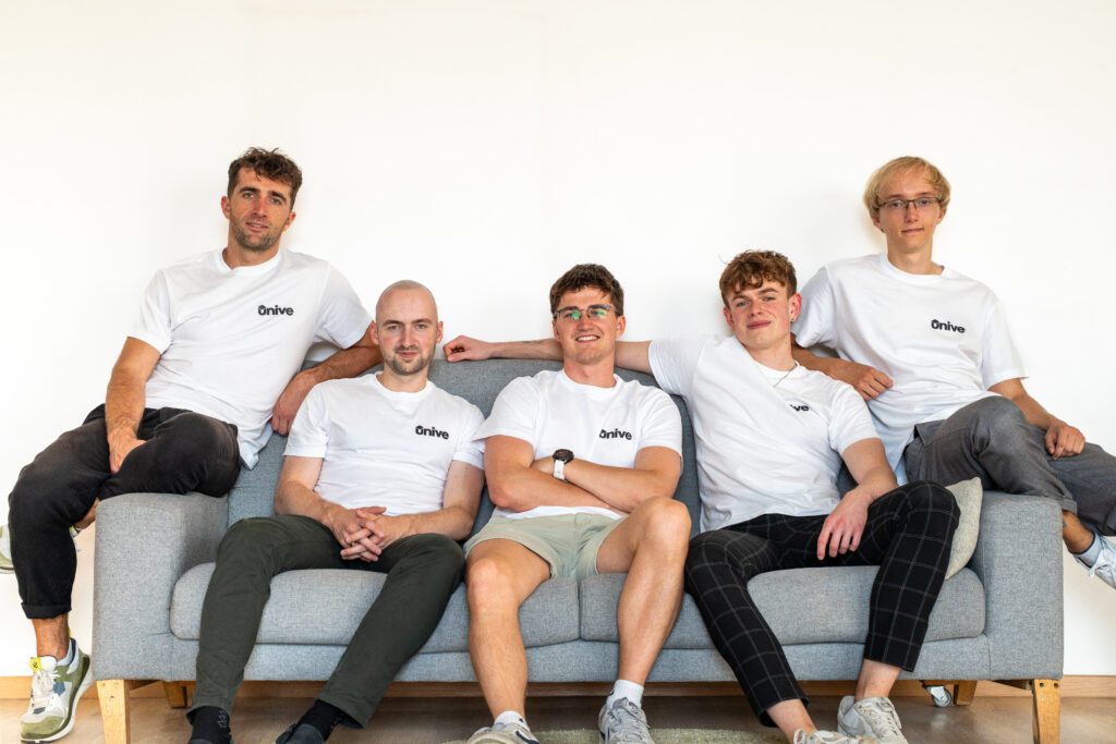 five men sitting on the sofa with white t-shirt looking to the camera